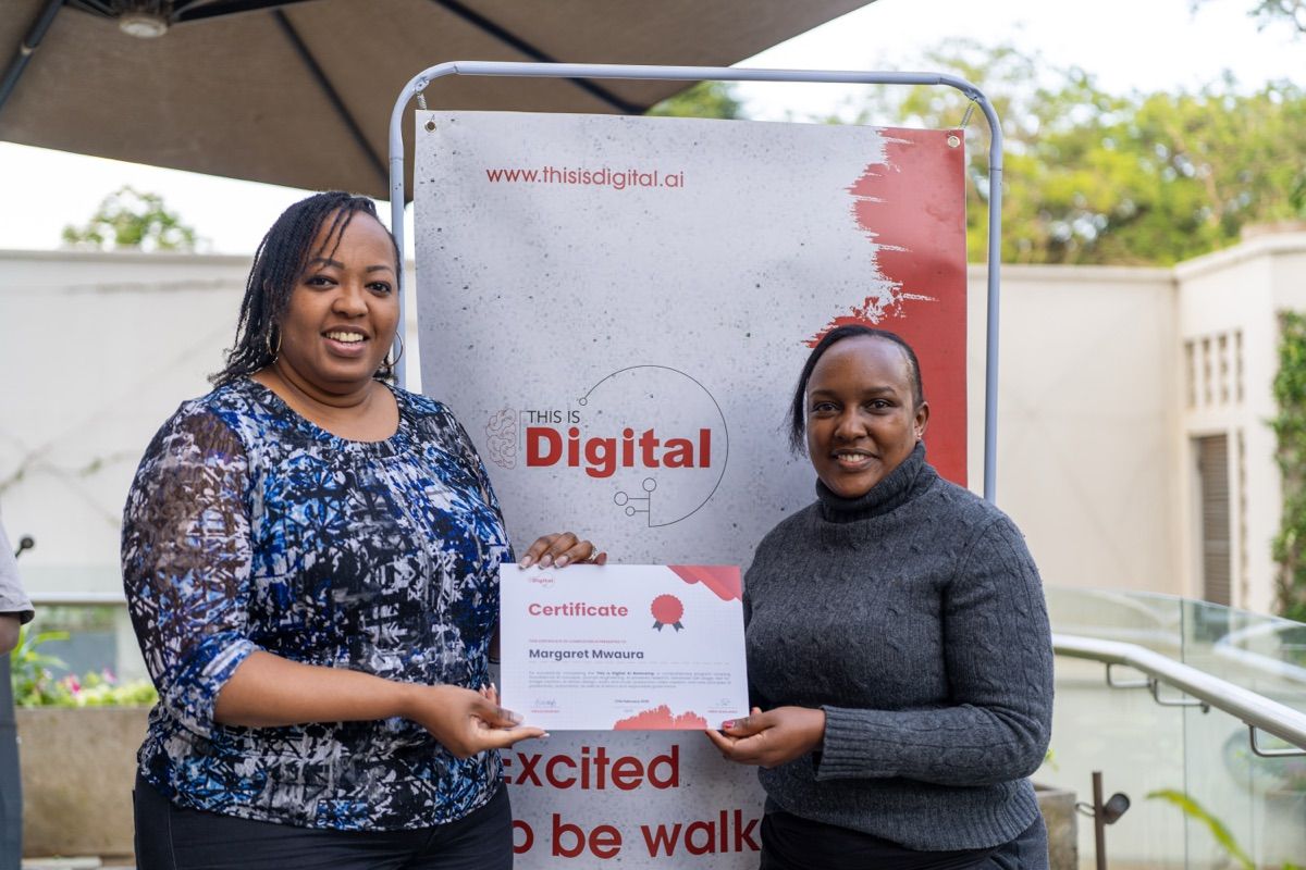 Two women holding a named TID completion certificate in front of a This Is Digital branded banner