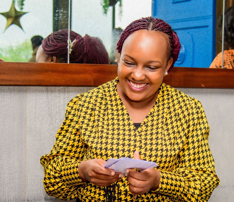 Carol Nyambura smiling as she reads through name cards at a This Is Digital community event