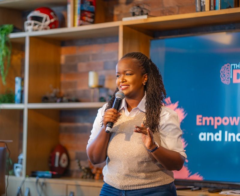 Grace Murugi speaking on stage with a microphone, a This Is Digital "Empowering" slide visible behind her