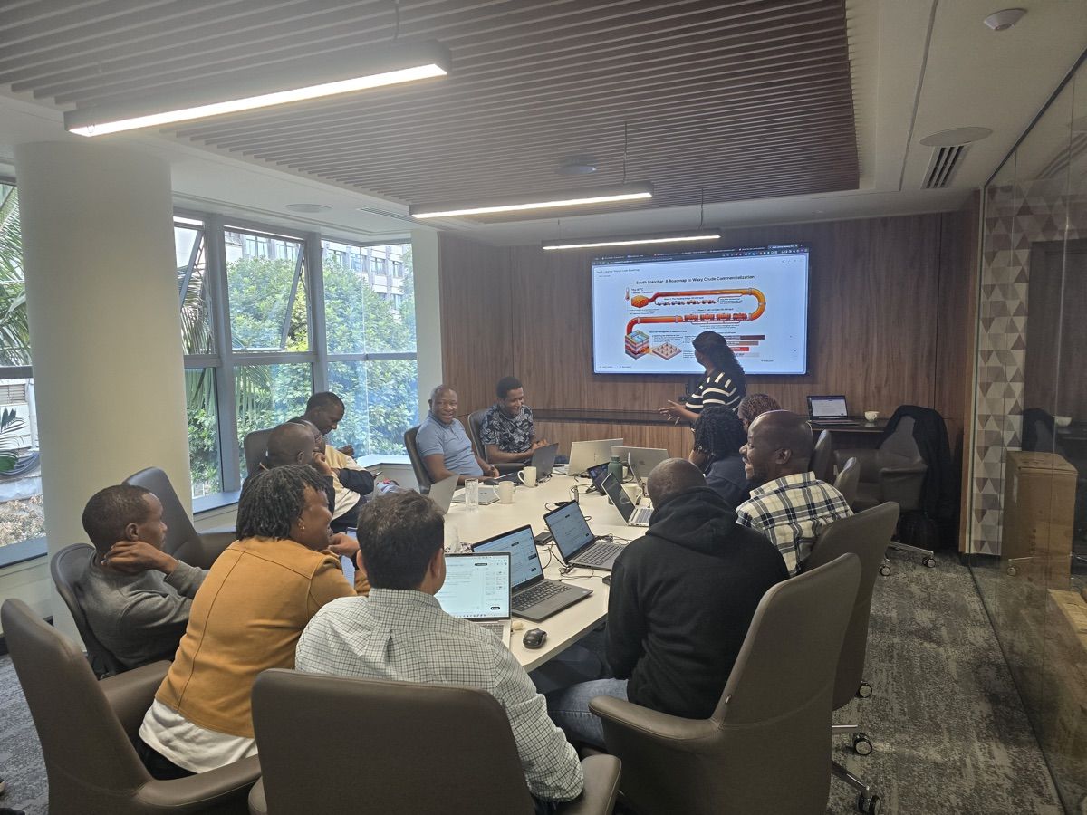 Participants seated around a boardroom table with laptops during an in-person AI training session